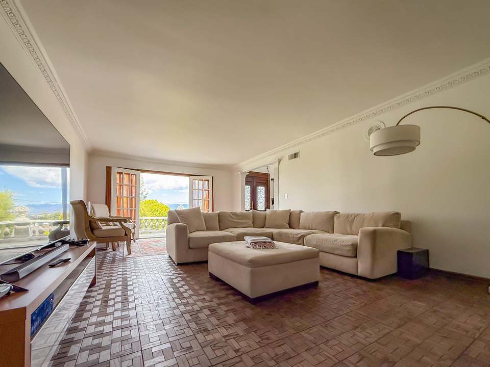 Living room with a large sectional, ottoman and 75-inch TV, French doors to the terrace