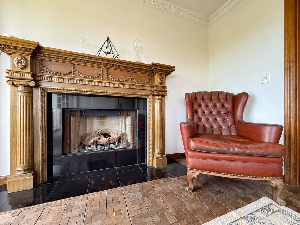 Carved wood fireplace beside a vintage tufted leather armchair